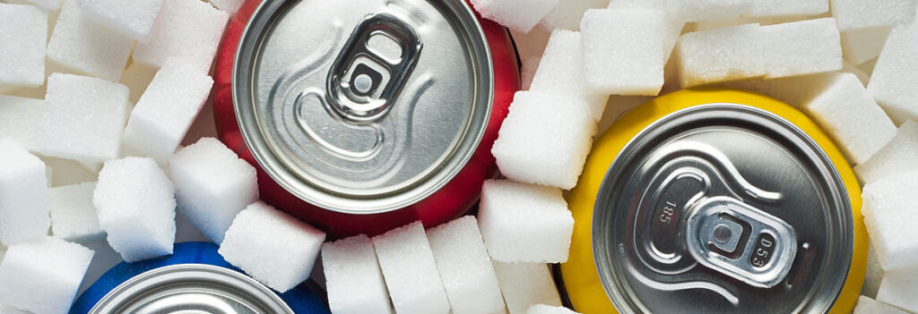 Tops of cans of soda surrounded by sugar cubes