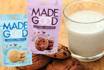 packages of Made Good cookies in front of a glass of milk and cookies.