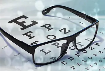 a pair of black rimmed glasses on top of a optical eye chart